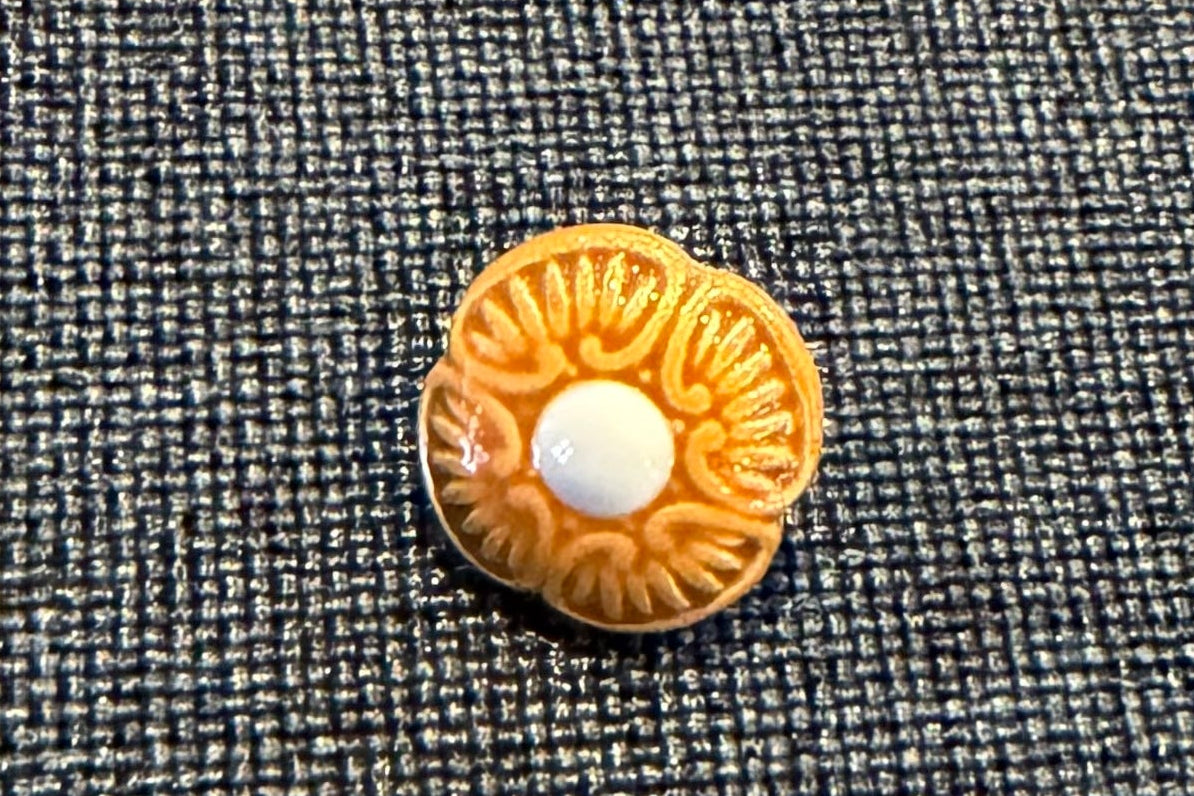 Decorative button with floral pattern on a textured fabric background