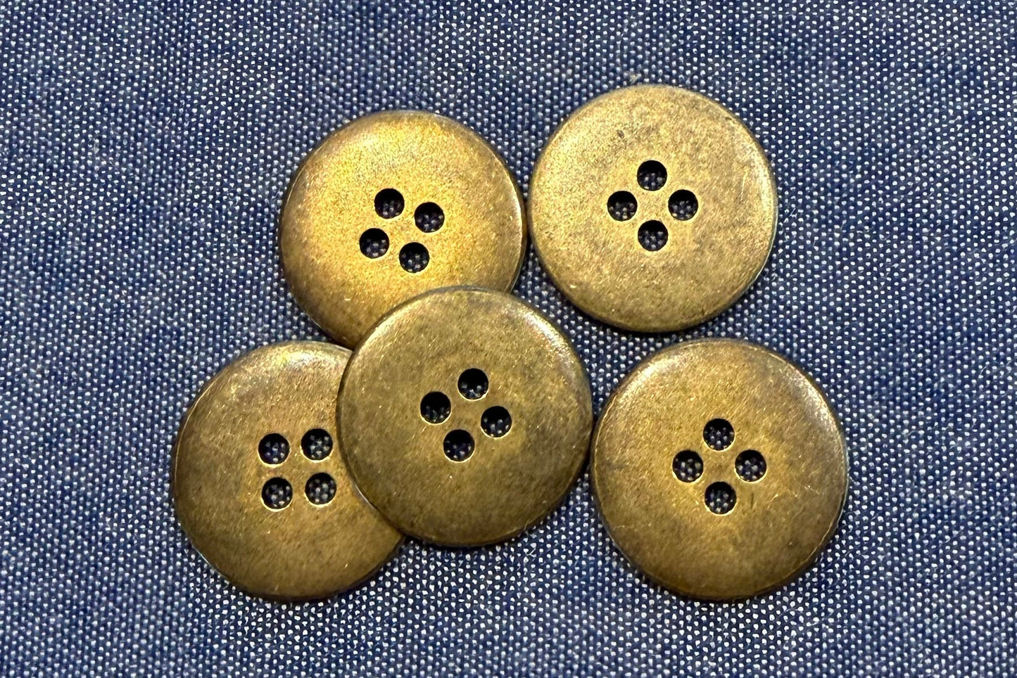 Five bronze buttons on a denim fabric background