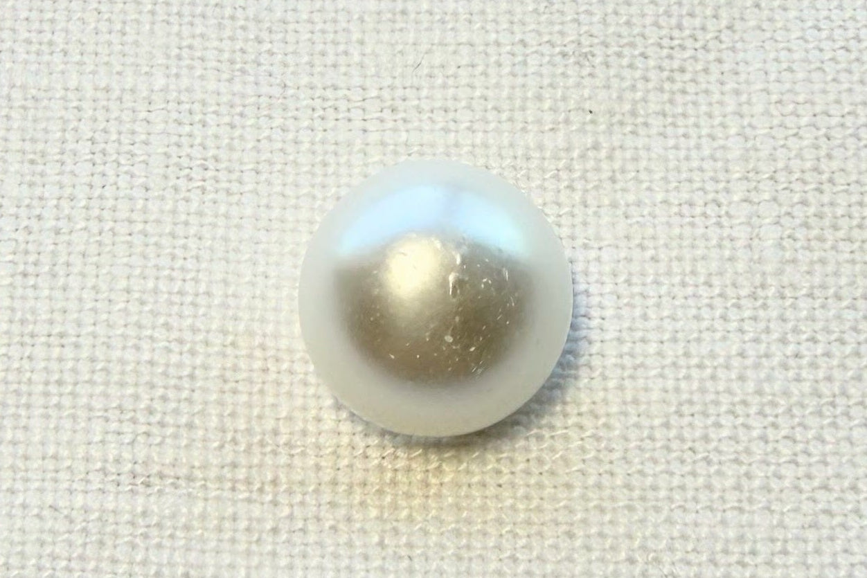Single pearl button
on a textured white fabric background