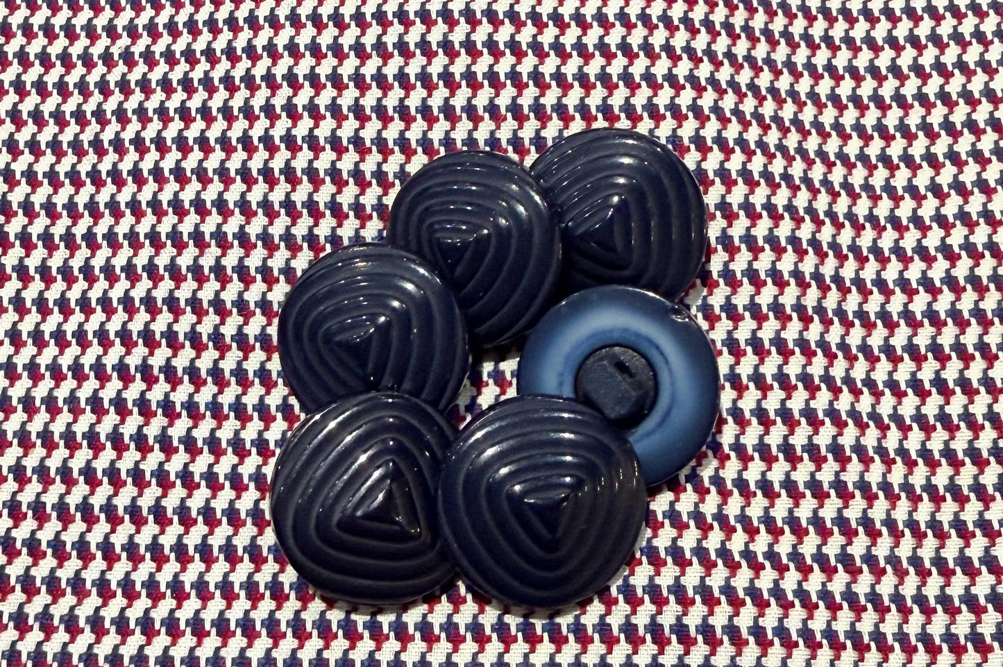 Set of blue plastic buttons on a patterned fabric background
