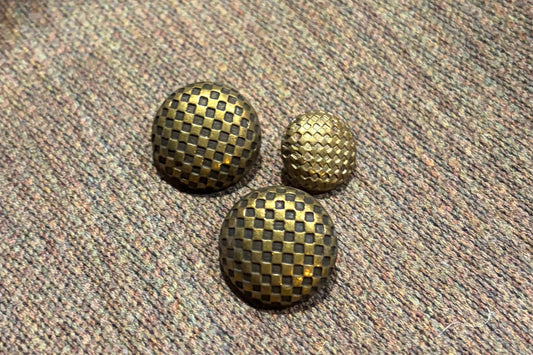 Three textured buttons on a textured fabric surface