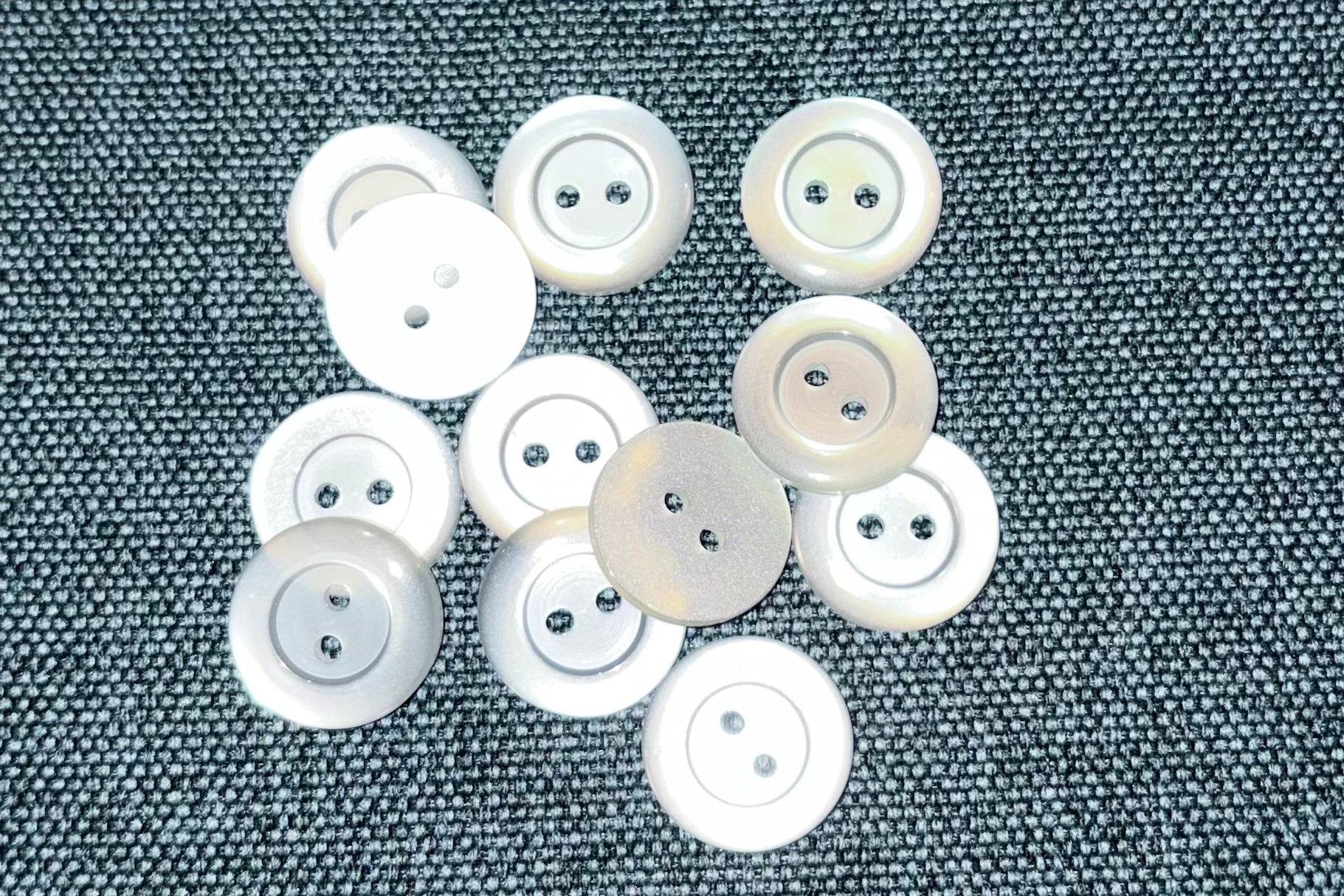 White buttons scattered on a textured gray fabric background