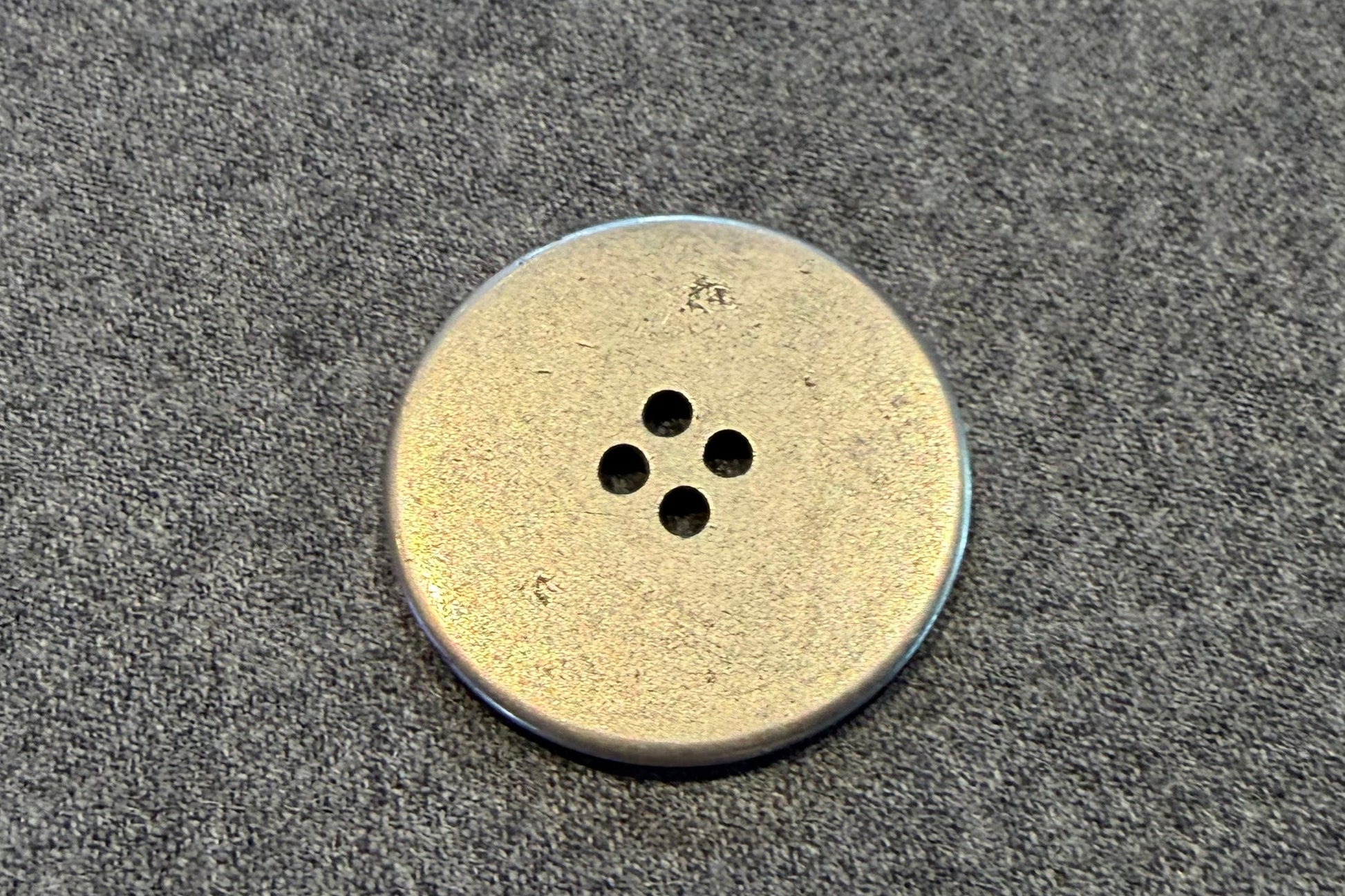 silver button on a textured gray surface