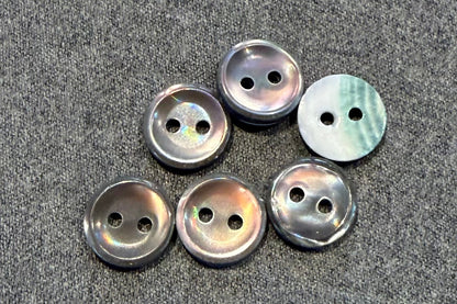 Set of six pearly grey buttons on a gray fabric surface
