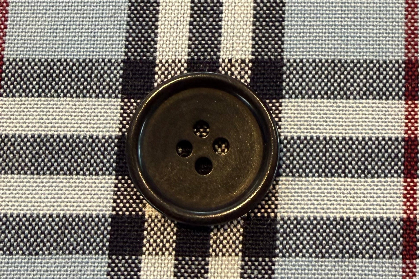 Close-up of a checkered fabric with a button on a gray background