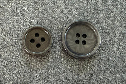 Two grey buttons on a textured gray fabric background