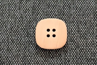 Tan button on a textured gray surface.