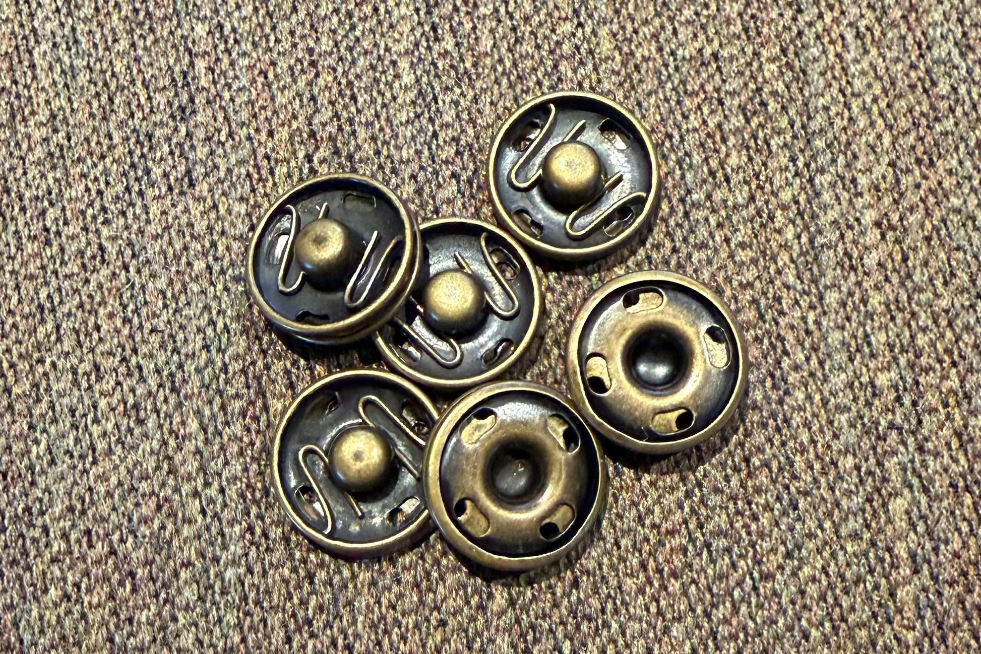 Set of brass snaps  on a textured brown surface