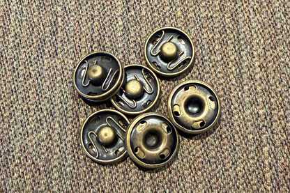 Set of brass snaps  on a textured brown surface