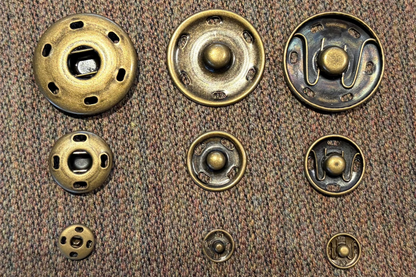 Set of brass snaps on a brown fabric background