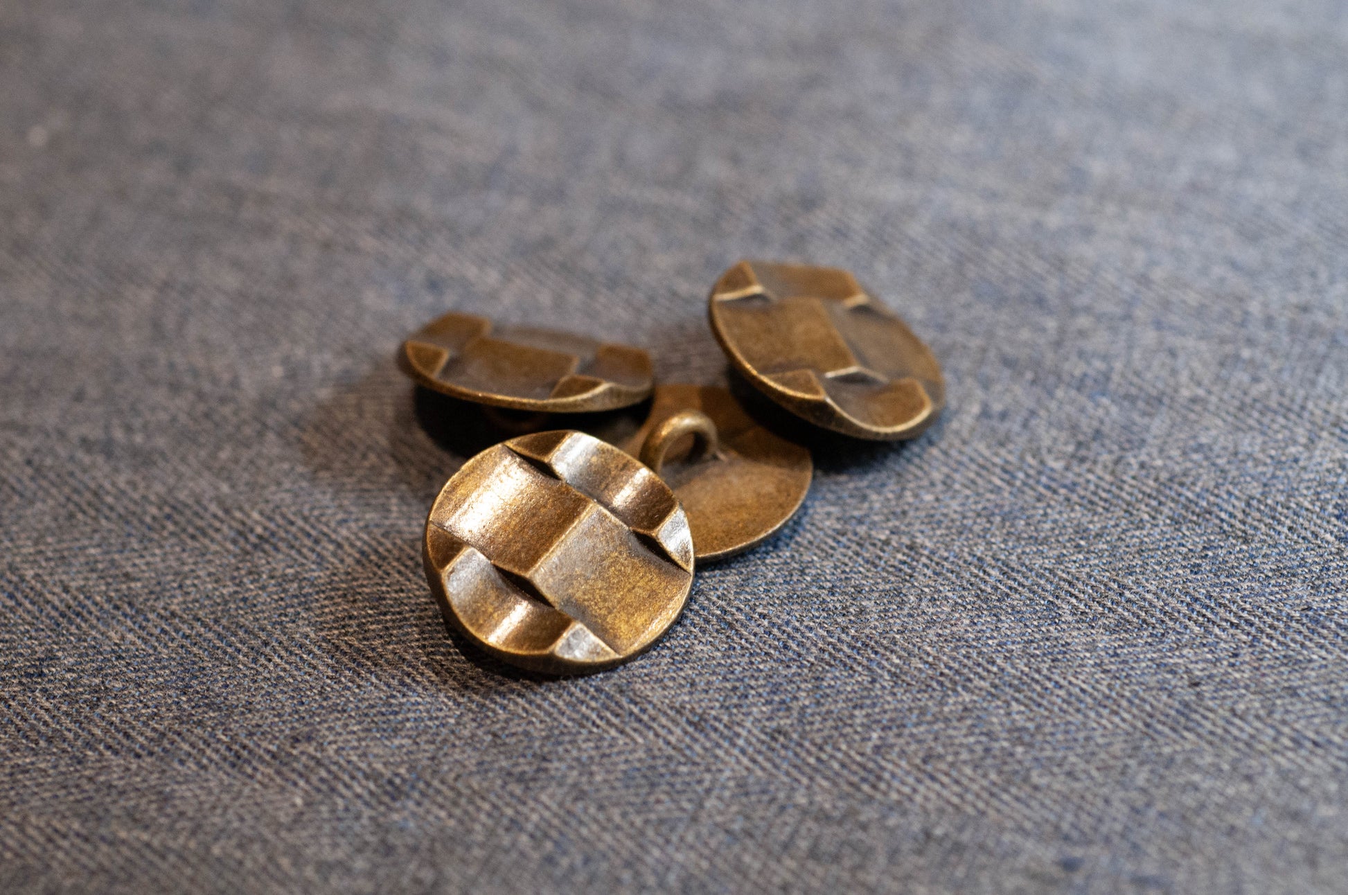 Three bronze buttons on a textured fabric background