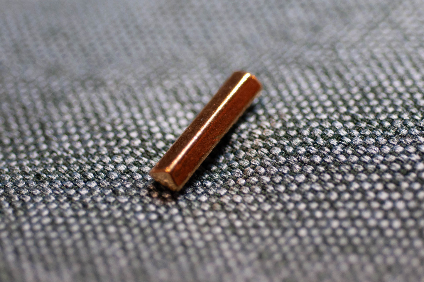 Bronze cylindrical button on a textured gray fabric background